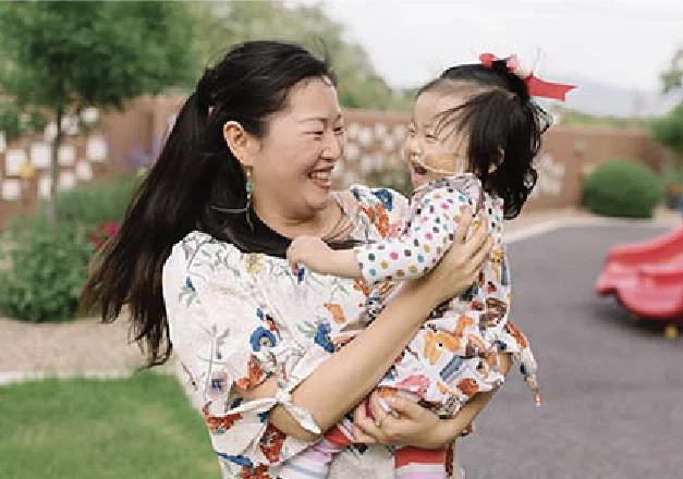 A mother holds her child closely while playing together on playground